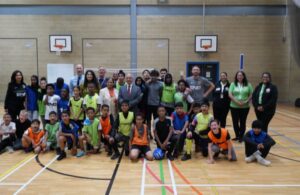 A group of people attending the HAF summer activity stand on a basketball court to pose for a photo with Councillor Nagpal.