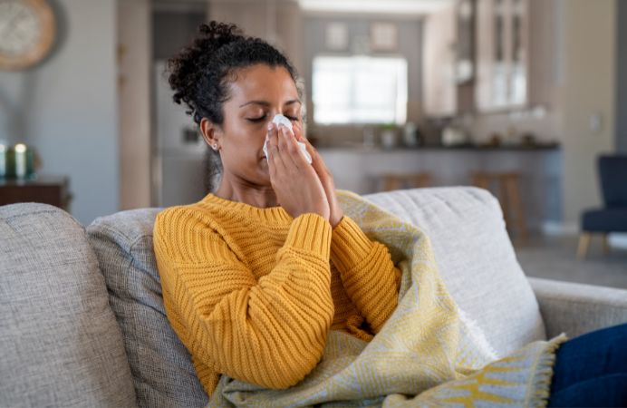 Women blowing her nose sitting on the sofa