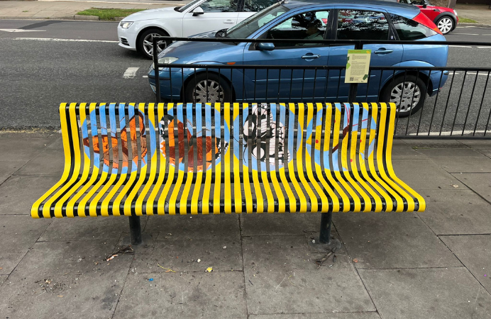 bench on pavement painted yellow with four colourful butterflies