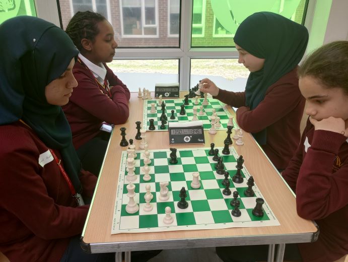 two pair of school girls sitting opposite one another playing chess