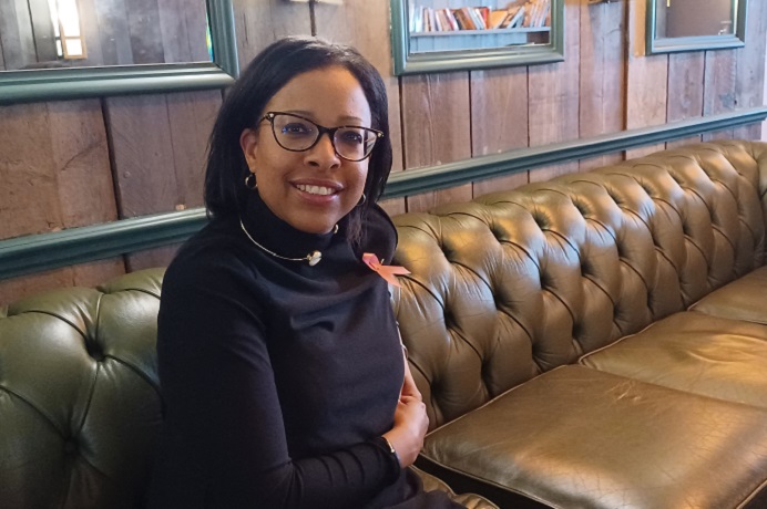 Black woman, sitting on a green sofa, smiling