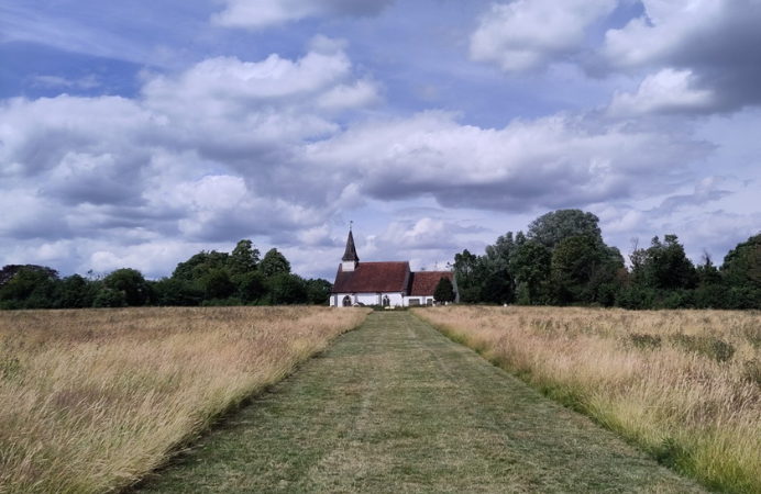 Green field of Belvue Park in Northolt with a church at the end