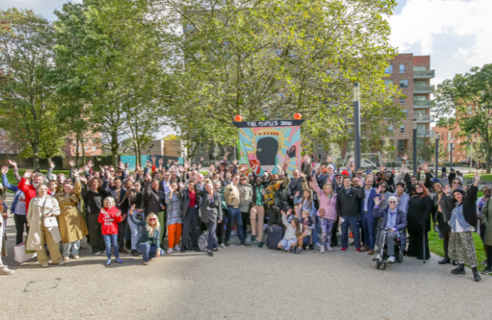 A group of people smiling and waving in front of trees