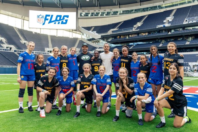 Girls from Ealing Fields and Stadtteilschule am Heidberg in their NFL sports kits posing for a picture at Tottenham Hotspur Stadium, where they played