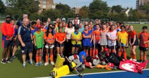 Group picture of Ealing Hockey Club members posing on the pitch