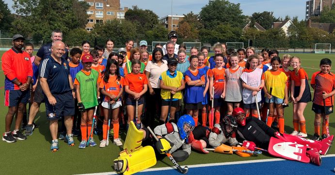 Group picture of Ealing Hockey Club members posing on the pitch