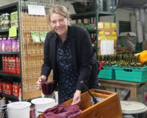 Cllr Knewstub with jug of crushed grapes, making wine at the grape and honey farm