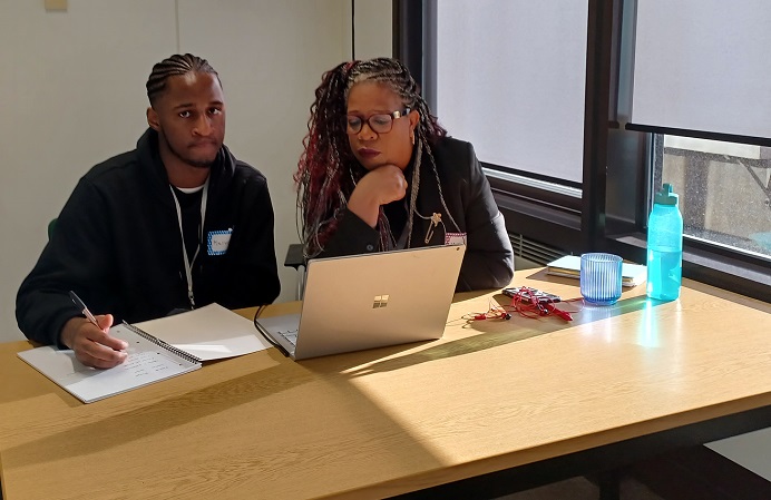 Black young male with Black female sitting looking at laptop