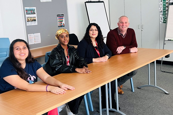 3 women and 1 man sitting at a desk