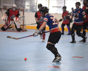 group of children playing  hockey with a ball in a sports hall