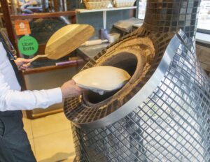 hands taking bread out of clay oven at Boof restaurant