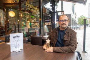 restaurant owner sitting outside restaurant with high five award