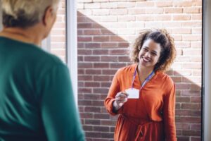 female resident opens door to a smiling woman showing id
