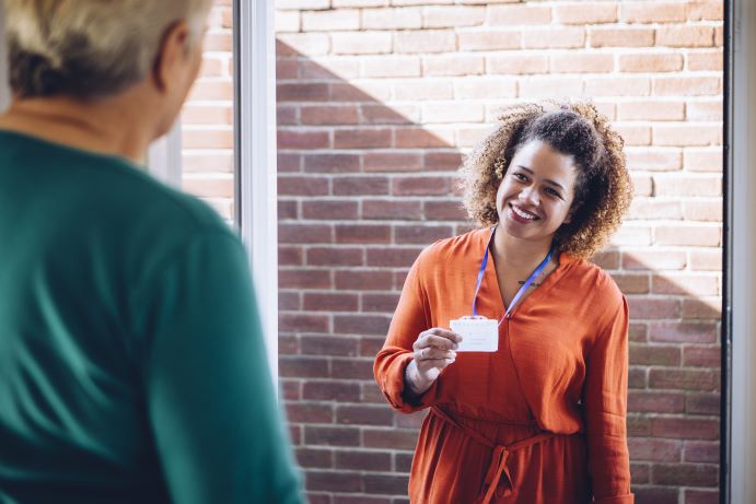 female resident opens door to a smiling woman showing id