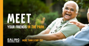 A older man sitting and laughing with another man outdoors