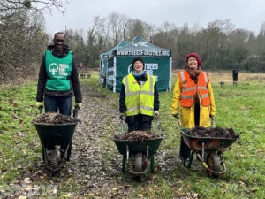 A man and two two women planting trees smiling at the camera