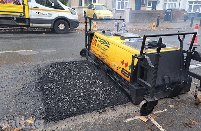 A long yellow rectangular machine fixing road potholes with a thermal treatment