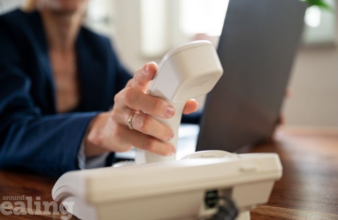 Image of person picking up receiver on landline phone