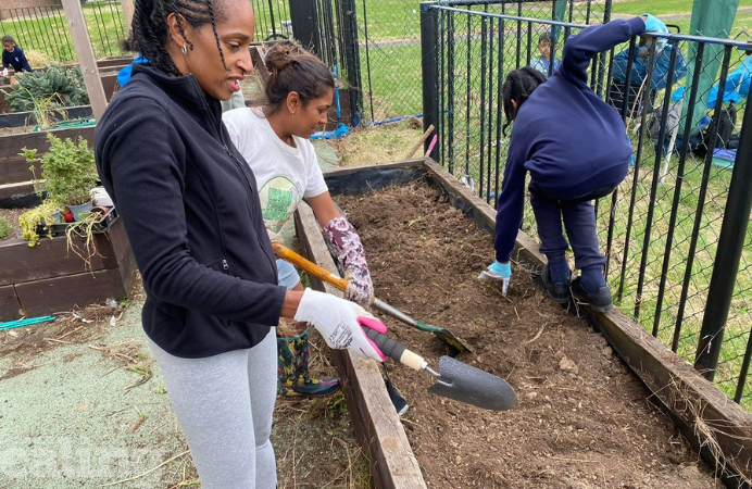 Two women with spades and young boy planting.