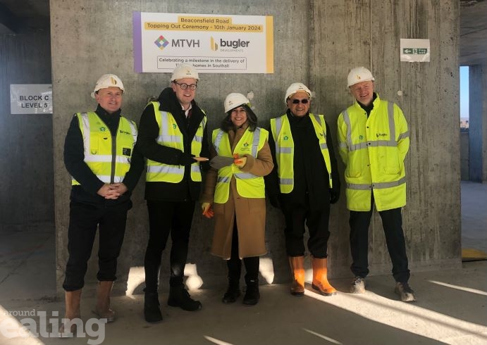 5 people standing in a row in hi vis and hard hats at a topping out ceremony