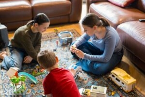 3 children sitting on the living room floor playing with toys