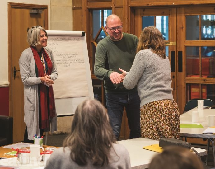 woman standing next to whiteboard and man shaking a woman's hand in congratulations