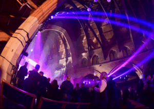 Multiple different colour light displays inside a church, with live music and an audience
