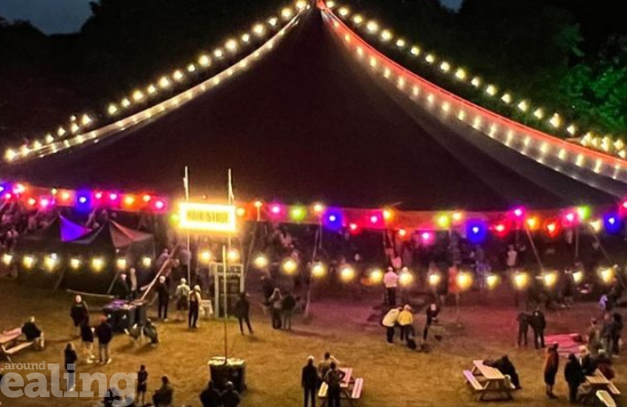 Marquee at night for an event with people sat or stood outside