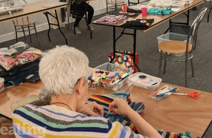 A lady with short grey hair mending clothes on a table.