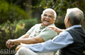 Two elderly men sitting among trees laughing