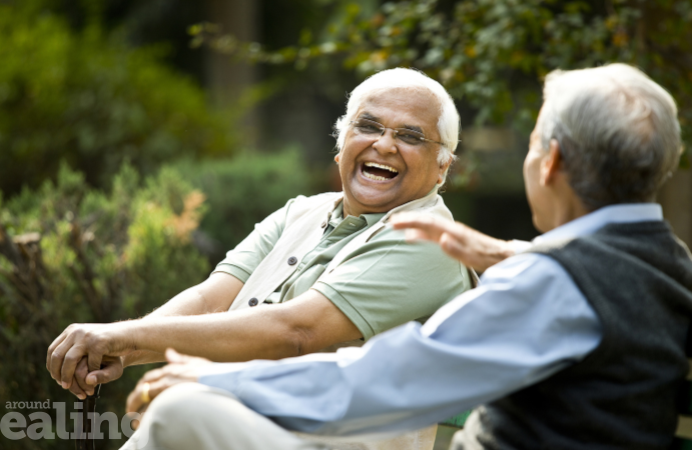Two elderly men sitting among trees laughing