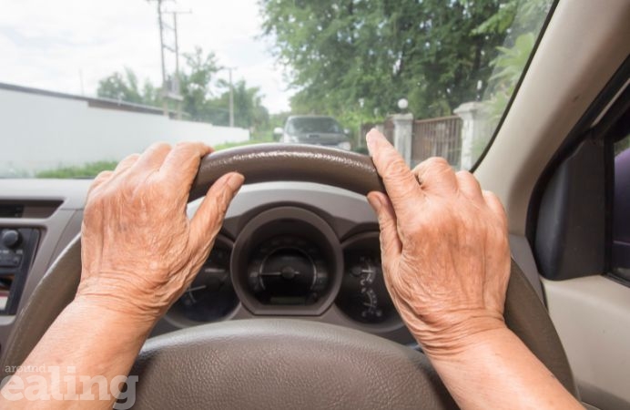 Elderly person's hands on a steering wheel of car
