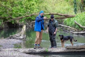 2 men and a dog standing by the Brent River in Hanwell