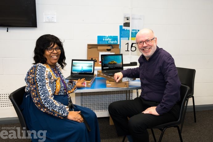 Ealing councillor Stephen Donnelly and Angela Doreen smiling and sitting at a table with two laptops.