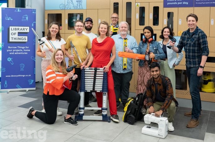 A group of people smiling at the camera holding household items.