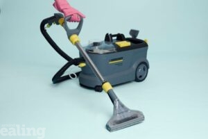 A carpet cleaner with a hand in a rubber glove holding the hose.