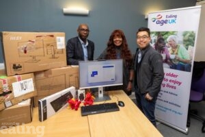 3 people standing at desk full of MSI computers that are being donated to charity