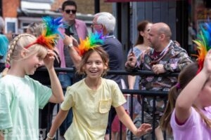 girls walking down street wearing brightly coloured hairbands with crowds in background