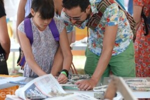 child and male adult leaning over table doing arts and crafts