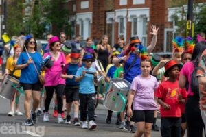 children and adults parading the street during the Hanwell Carnival procession