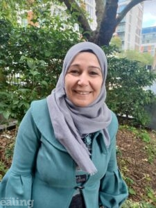 Picture of refugee Layla Othman smiling and standing outside wearing headscarf and green coat