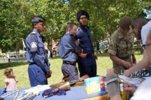3 cadets in blue uniform looking at musical instruments