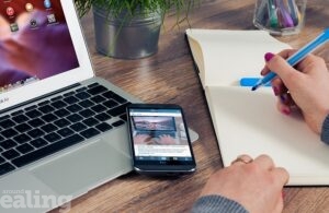 Working at a desk with a laptop, smartphone, and notepad
