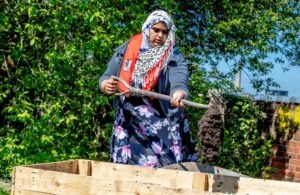 Woman using a shovel to pour earth into a box.