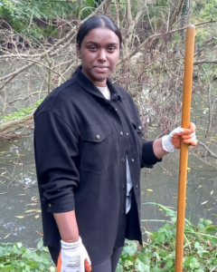 A woman poses with a shovel while helping build a home for animals at Hanwell Zoo.