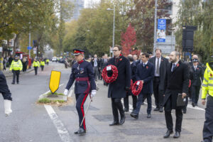 Group of people march in unison down Ealing street wearing poppies to commemorate Reembrace Sunday