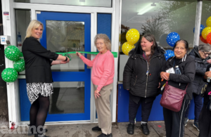 A woman stands beside three local women as she cuts a ceremonial ribbon at a doorway, marking the official opening of a new community space.
