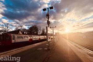 Tube train leaving Northfields Station as sun is setting