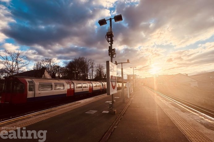 Tube train leaving Northfields Station as sun is setting