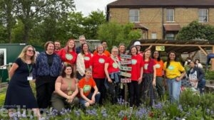 Group of people gathered in a garden setting wearing matching MindFood T-shirts and smiling